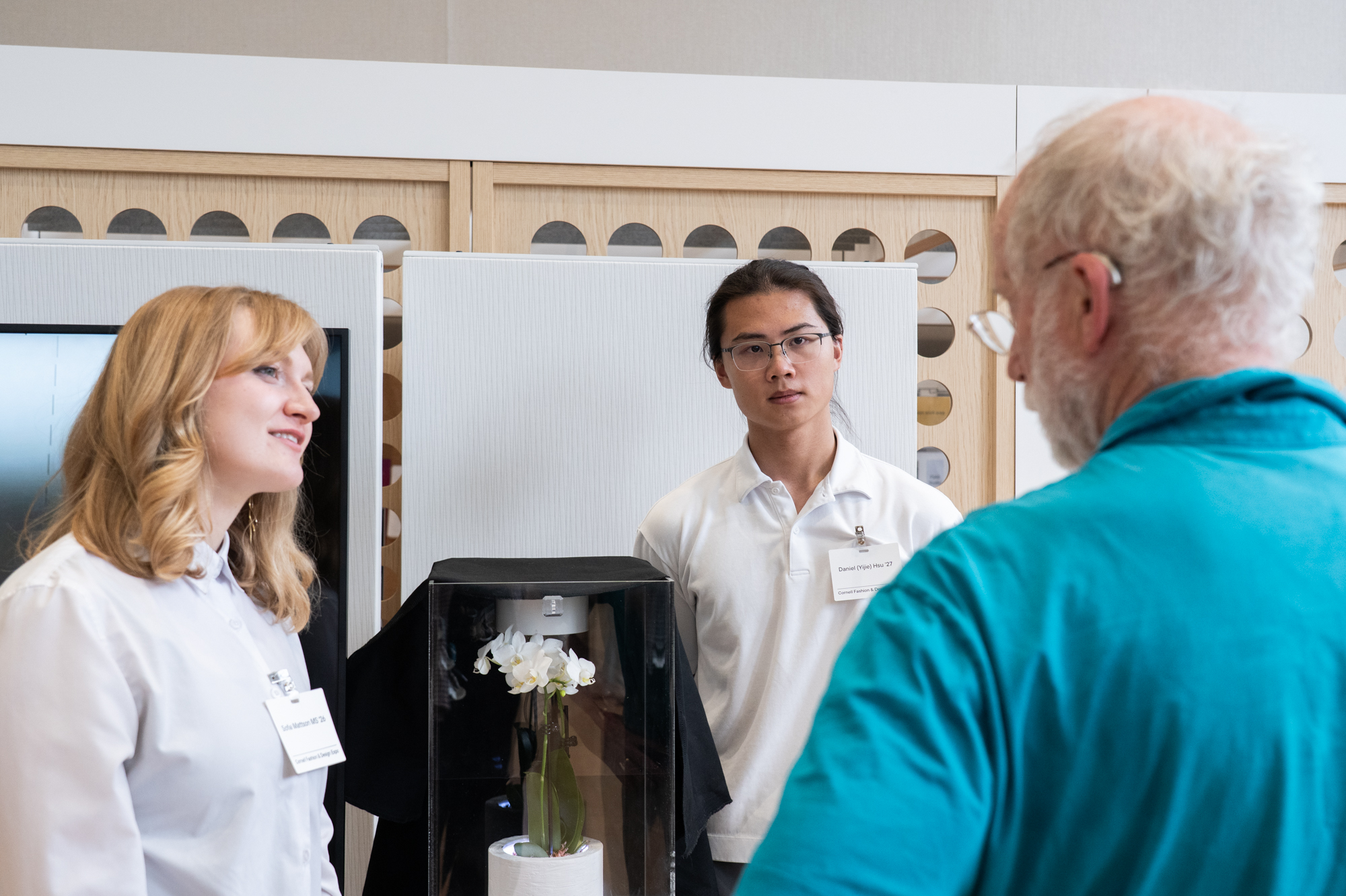 Students explant their design - a plant that purifies the air and notifies occupants when air reaches harmful levels to a faculty member
