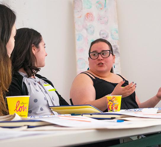 group of four people sit at a table talking