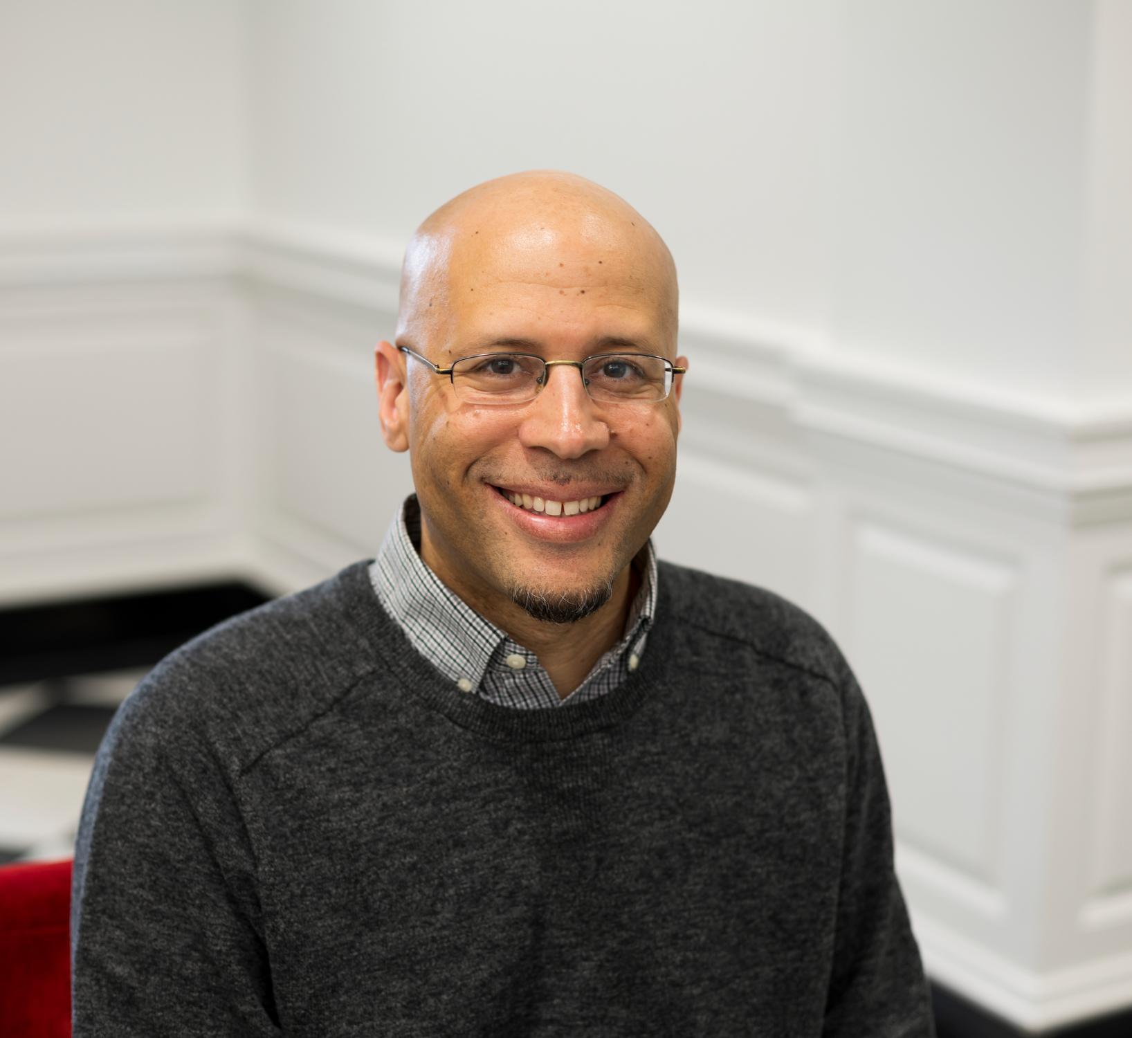 person in sweater and glasses smiling at the camera