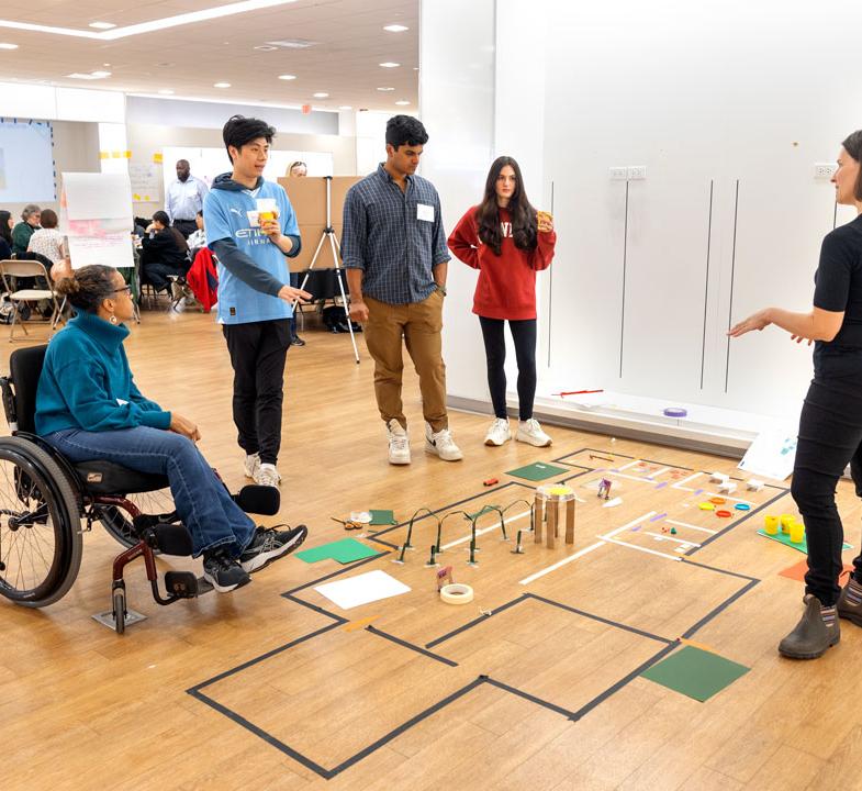 group of people in an open room looking at some plans on the ground