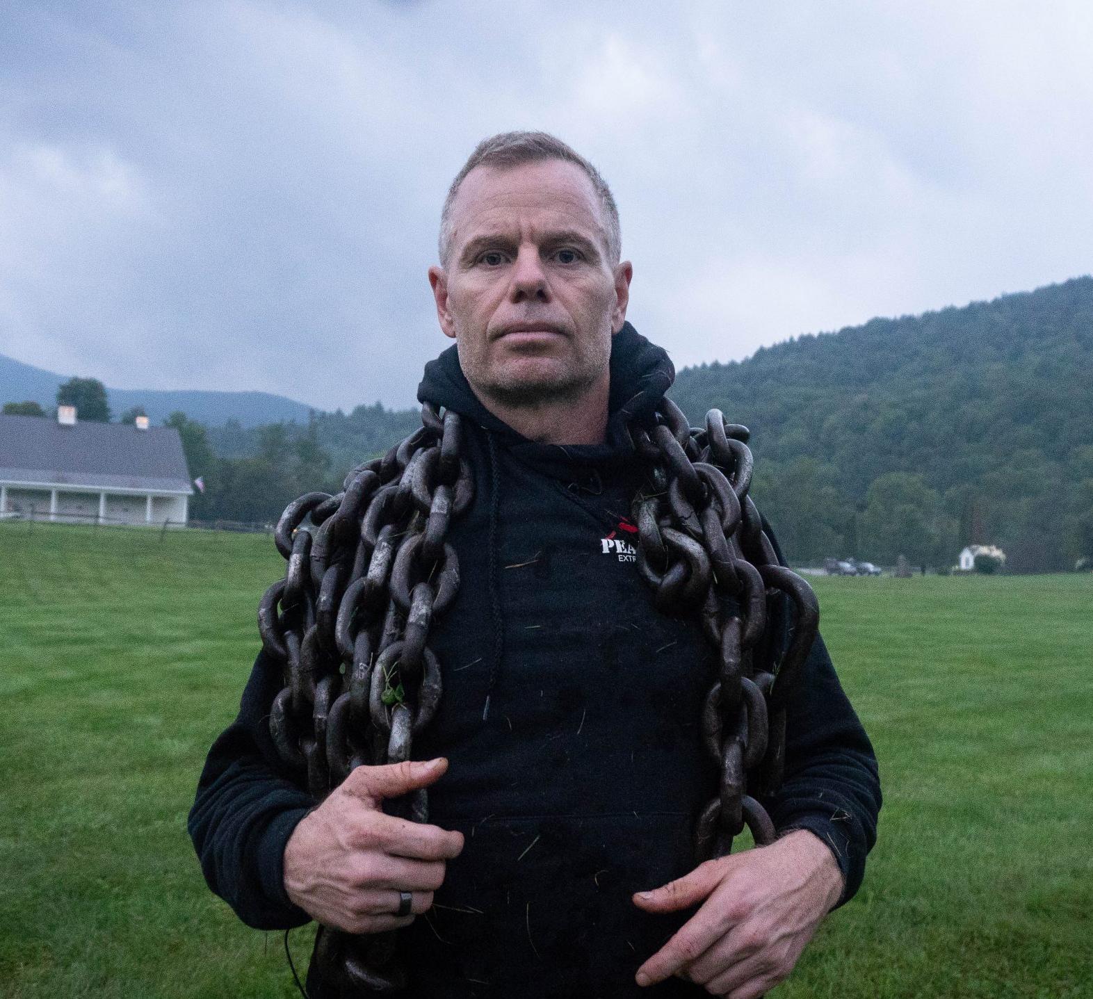 man on a hillside with a large chain draped over his shoulders