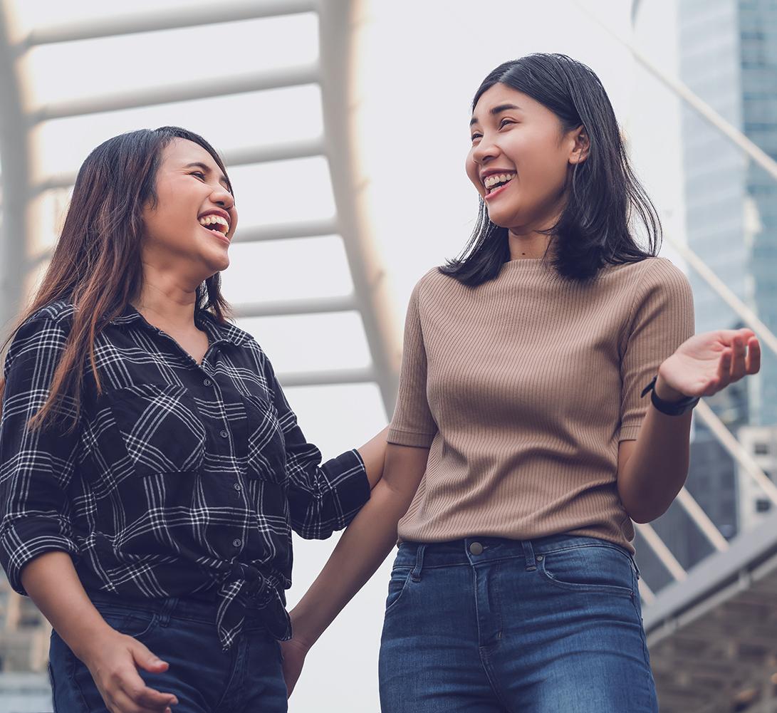 two women laughing outdoors in an urban setting