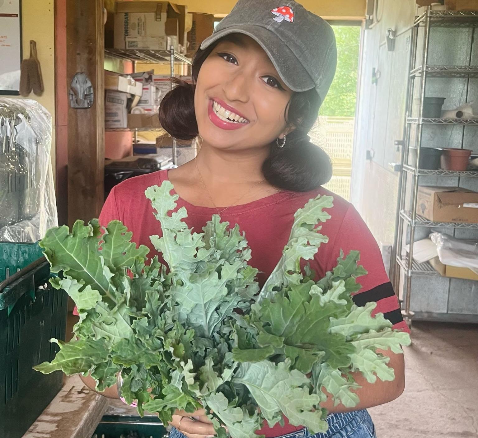 Student Esha Shakthy proudly holds a bunch of freshly harvested kale