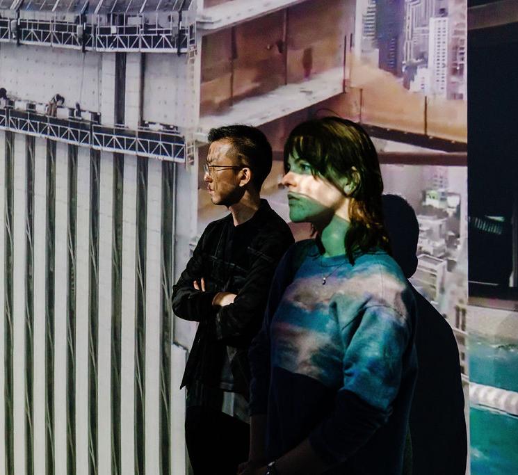 A teacher and student stand in front of a round screen projecting architectural images 