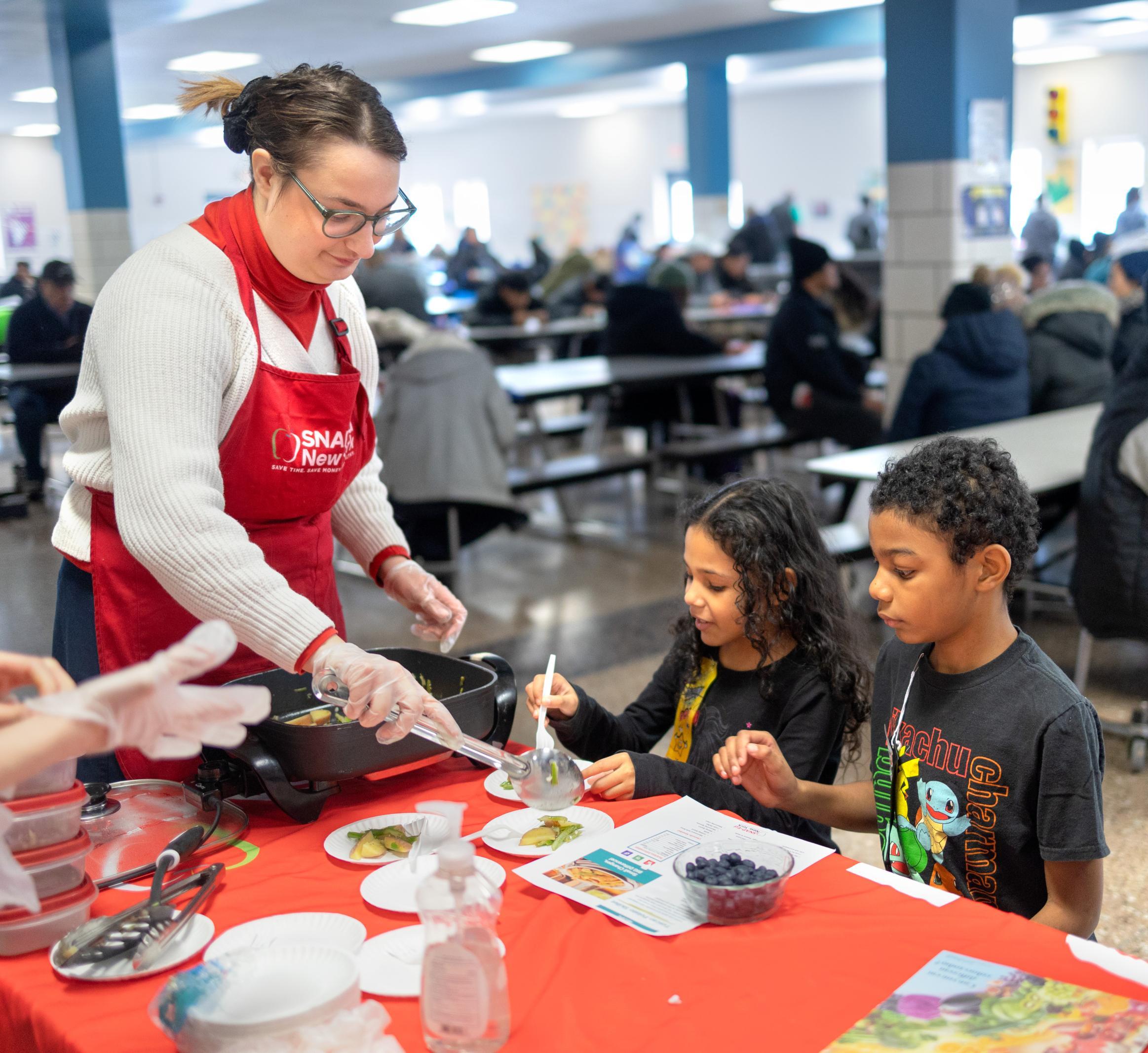 A SNAP educator cuts up fresh fruit for kids 