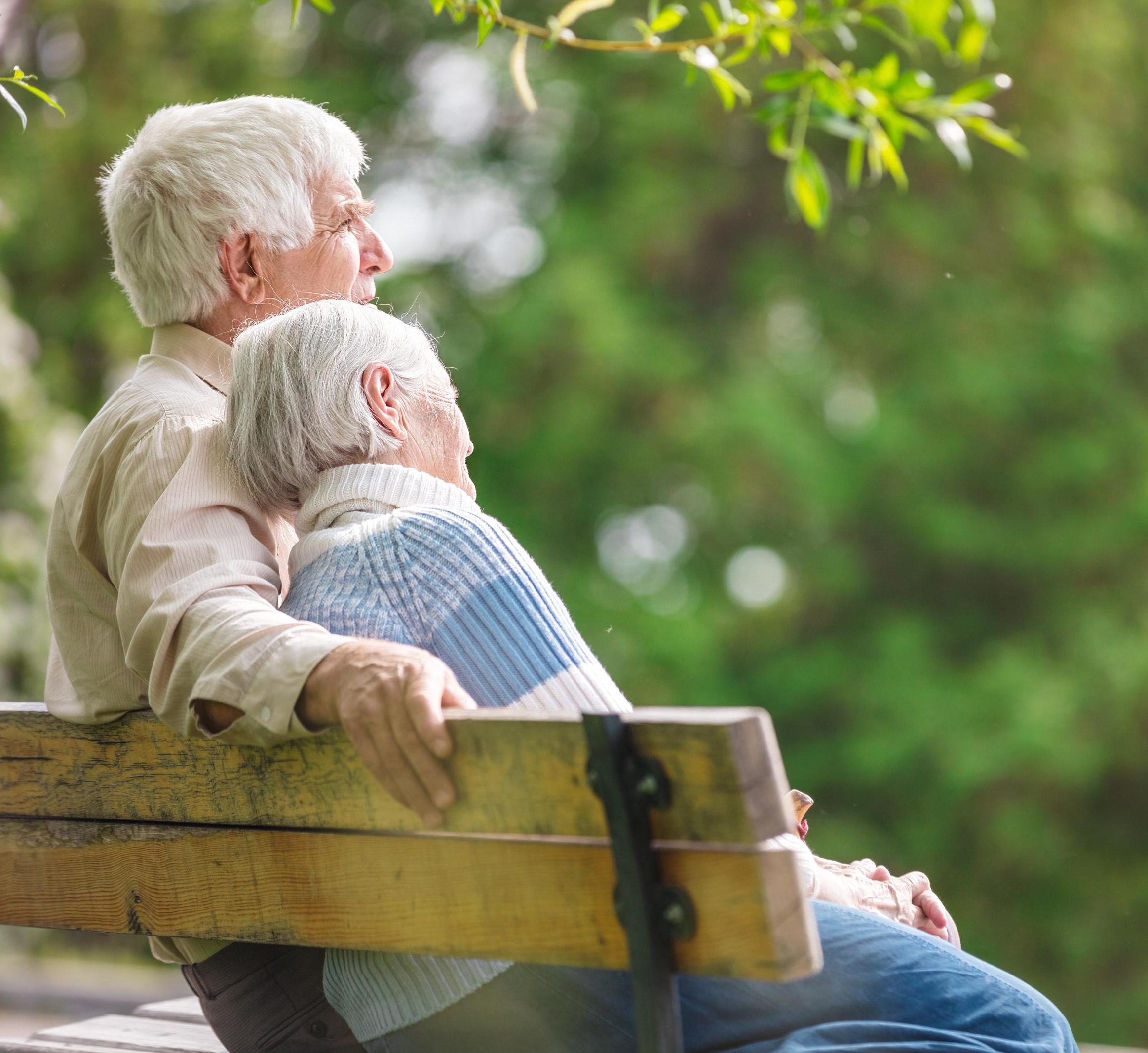 An older couple sits on a bench 