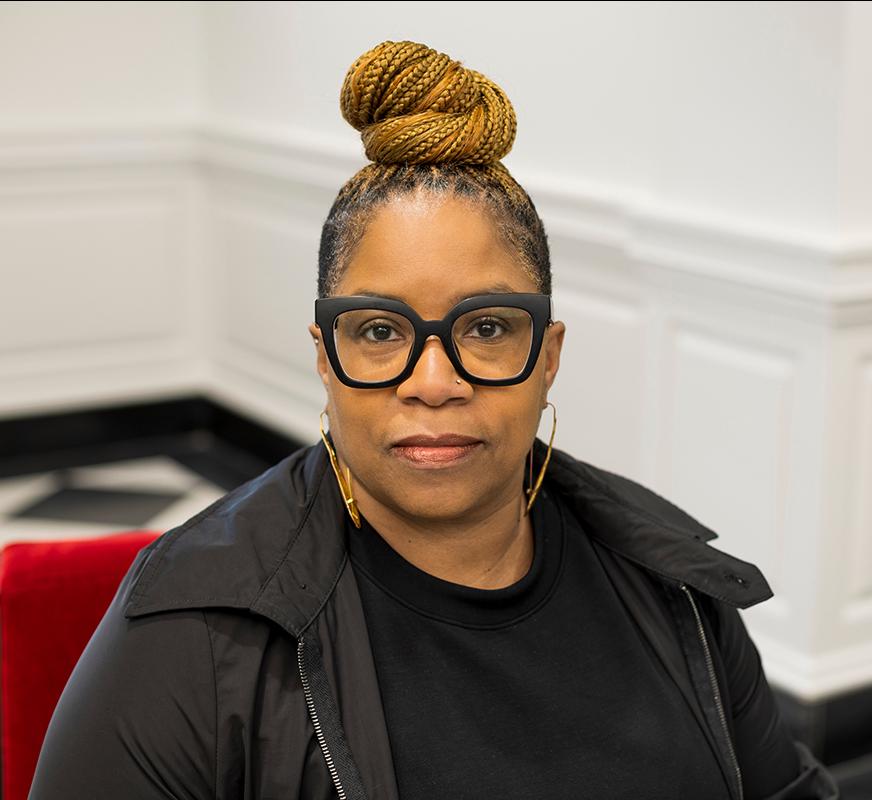 portrait of a woman in black framed glasses looking at the camera
