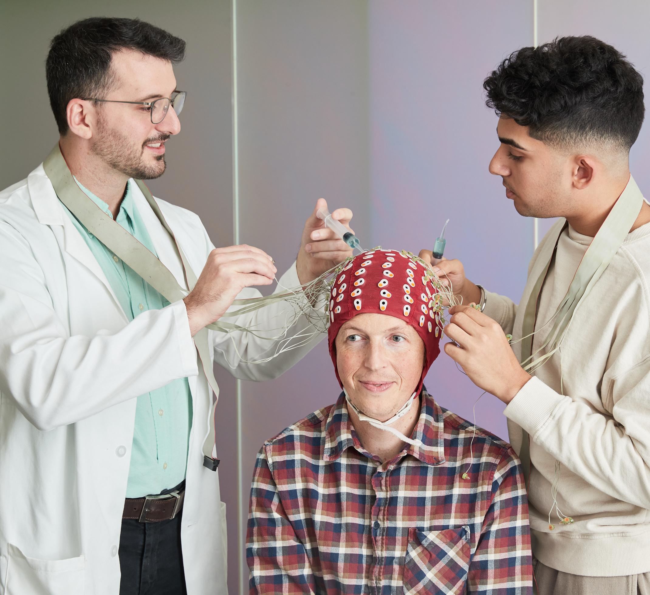 Two lab techs put an EEG cap on a patient