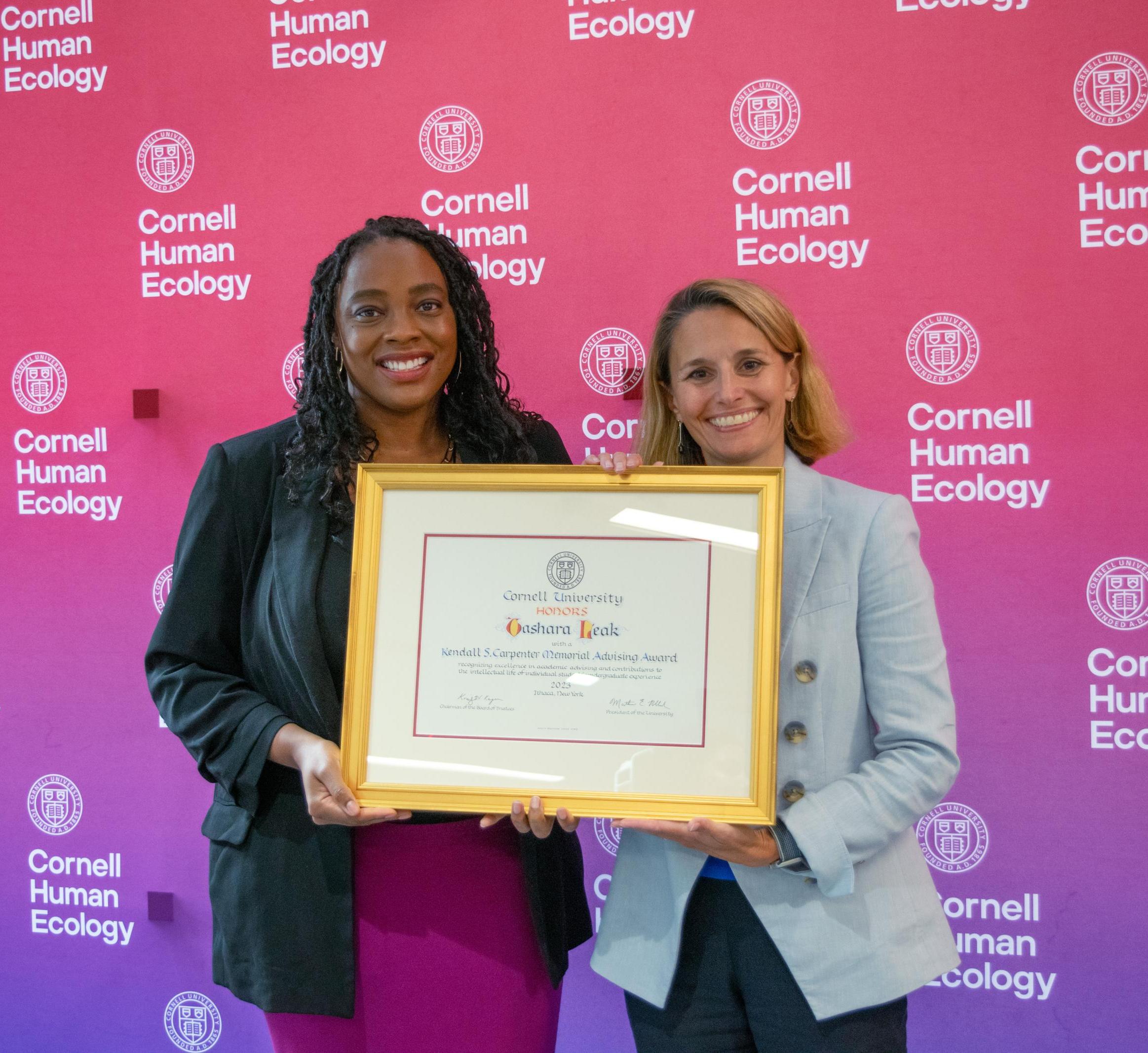 Tashara Leak and Rachel Dunifon pose holding the Carpenter Advising Award certificate