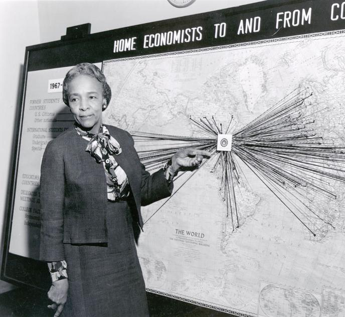 Flemmie Kitrell poses in front of a world map