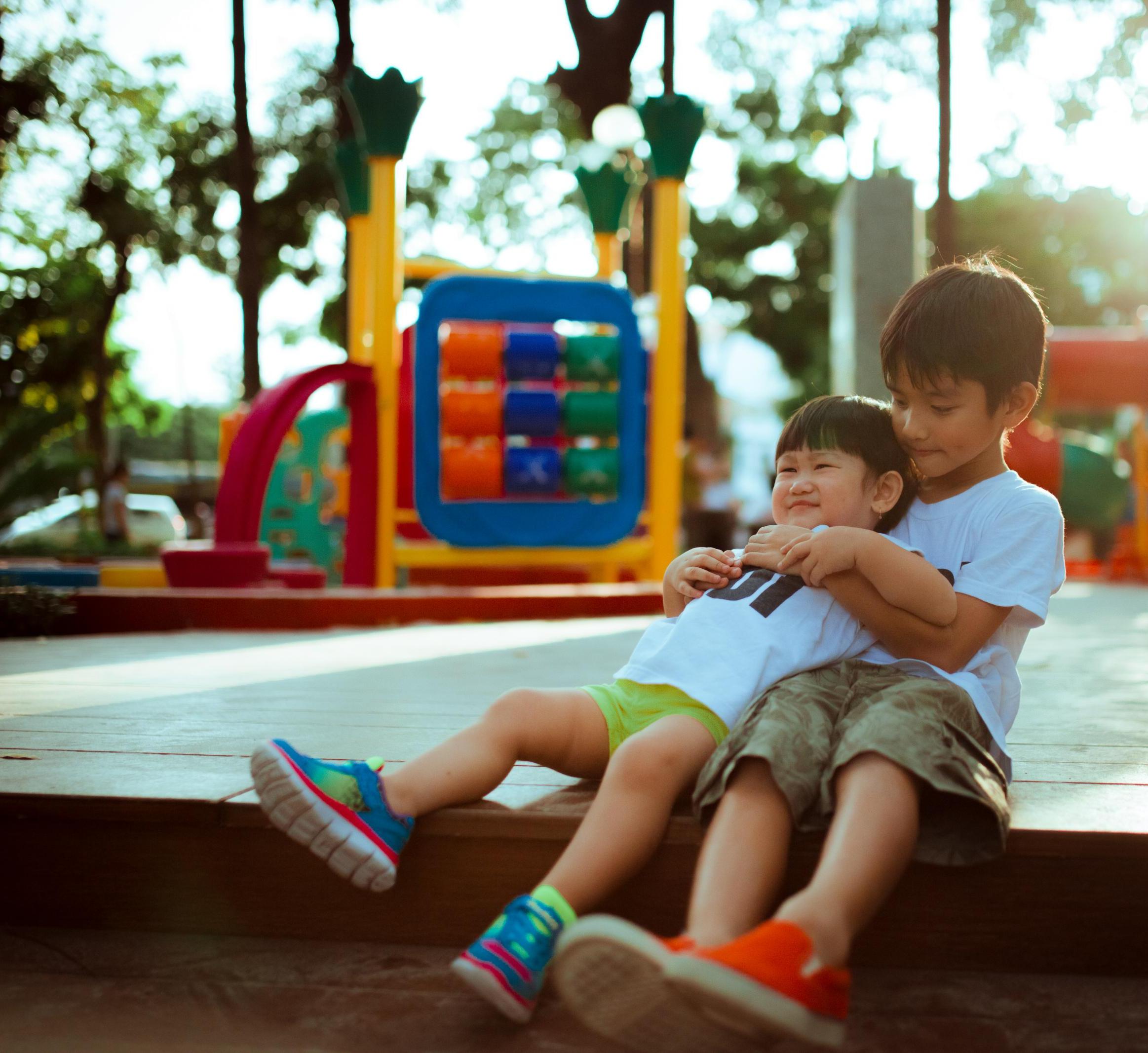 Two Asian children hug