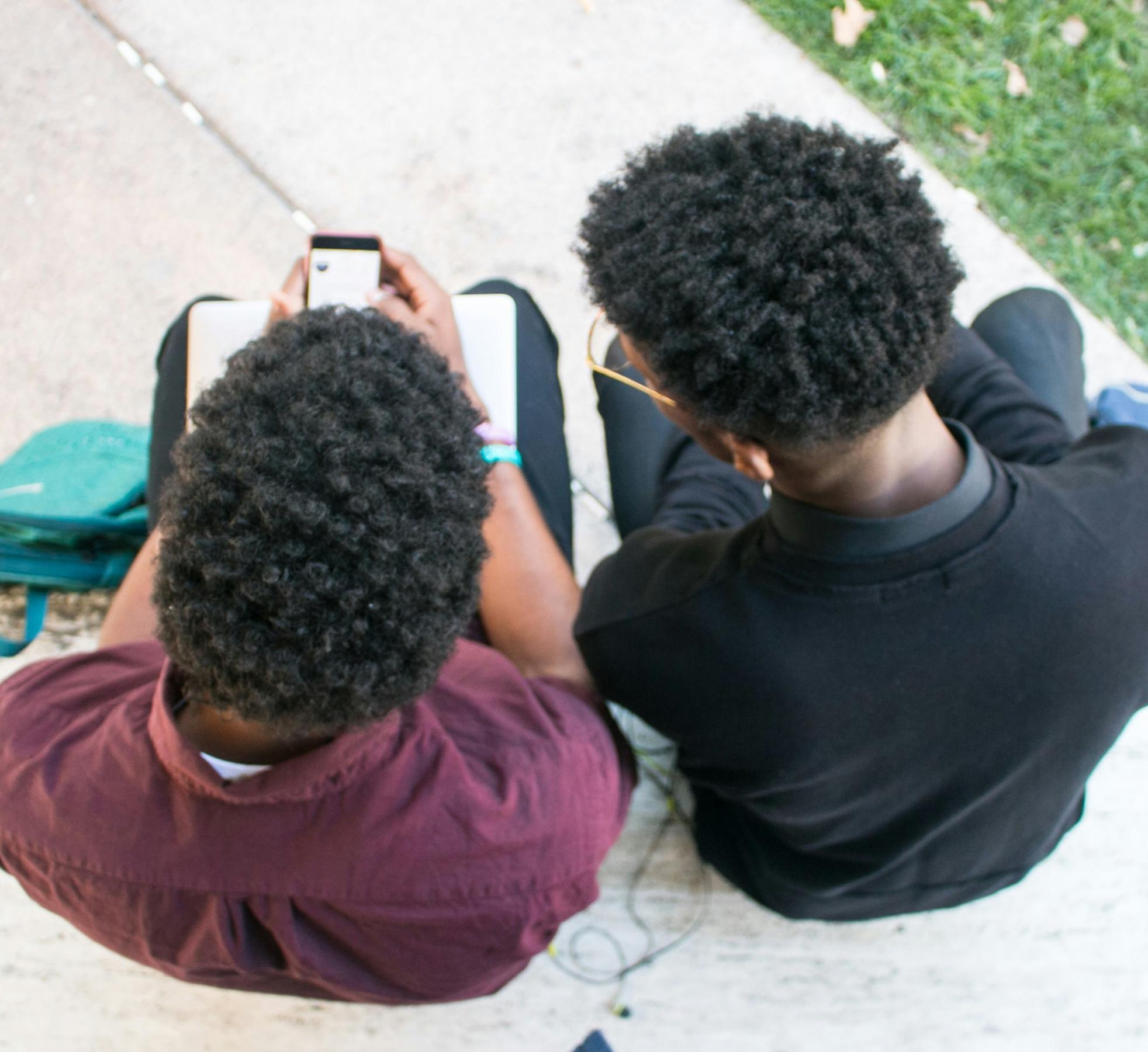 Two teens look at a cell phone together