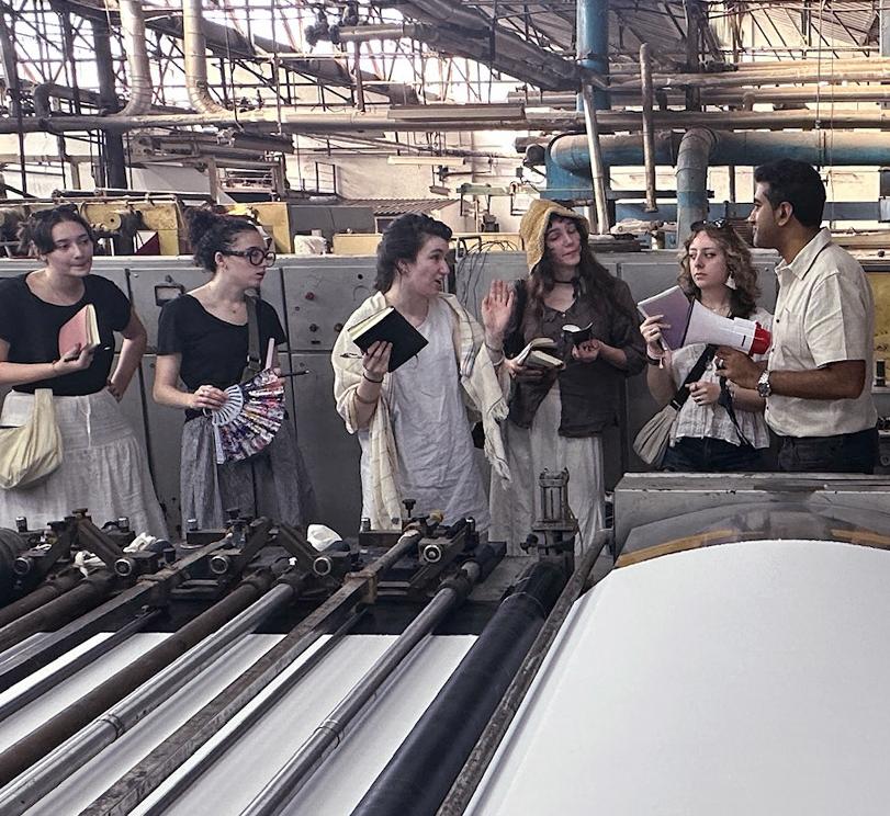 Students talk on a plant floor to textile workers