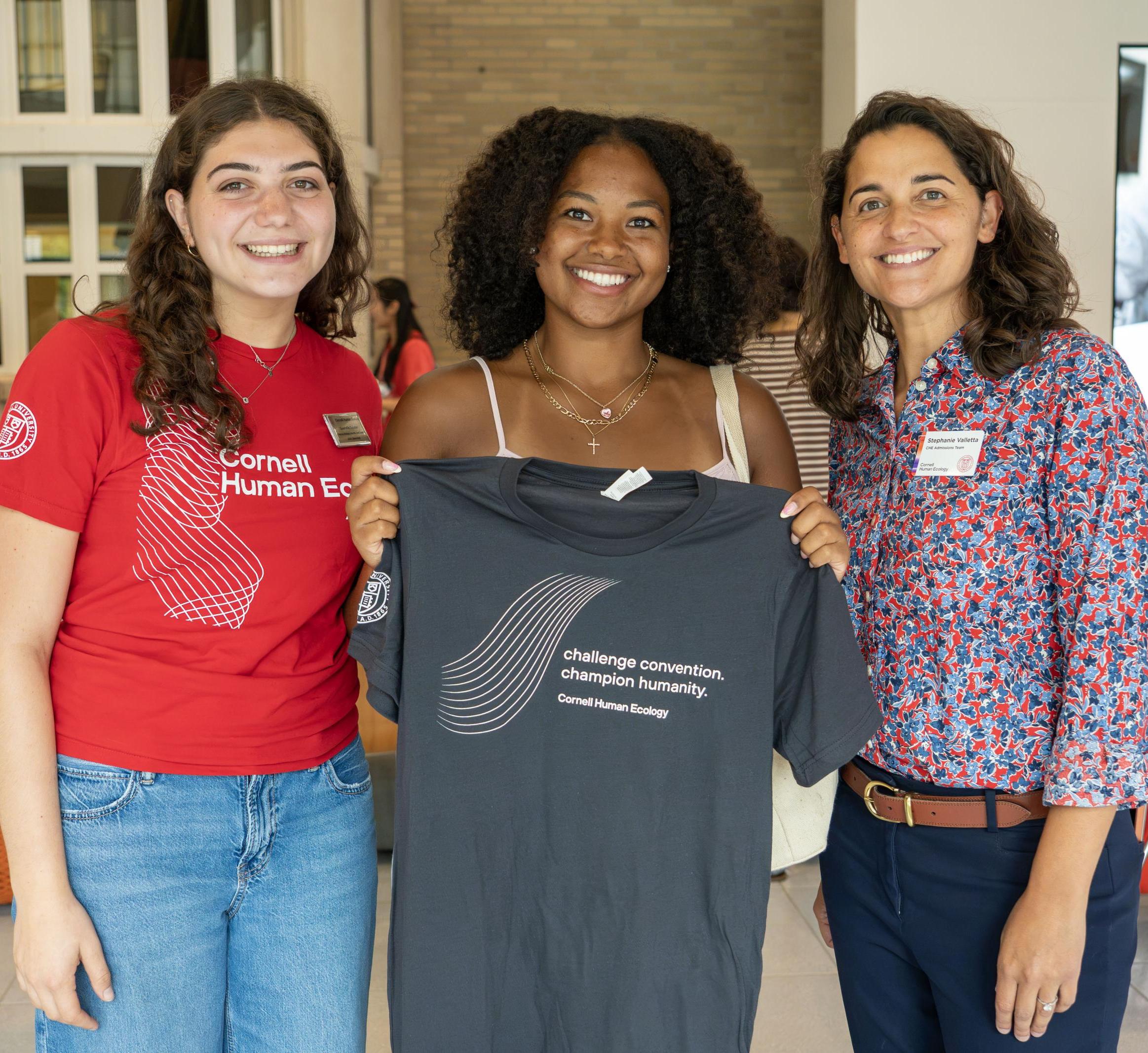 3 women a Orientation holding a CHE tshirt
