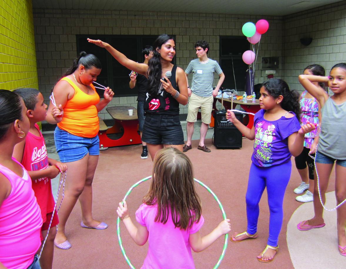 young person gestures while surrounded by children on a playground
