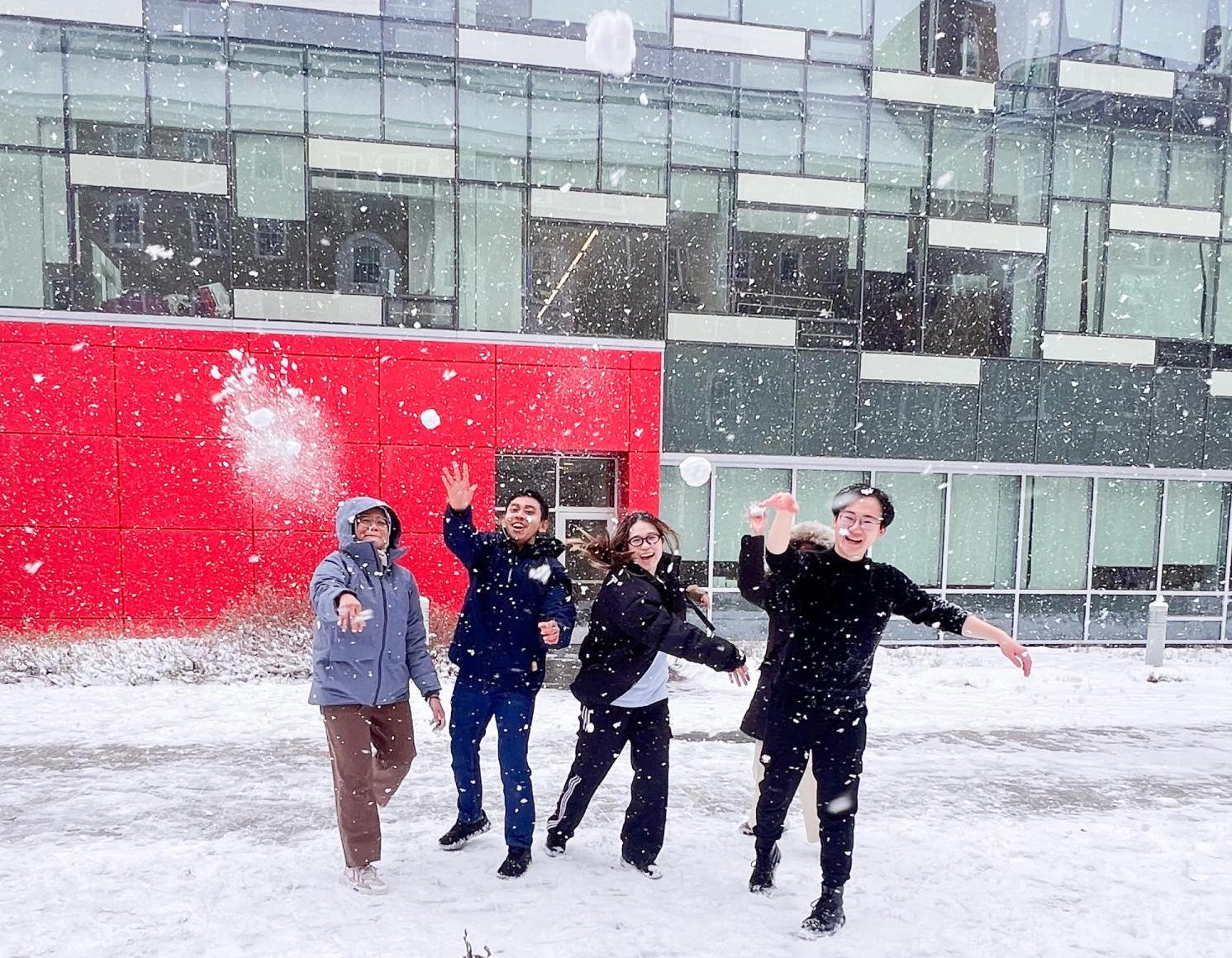 college students throwing snowballs in a courtyard