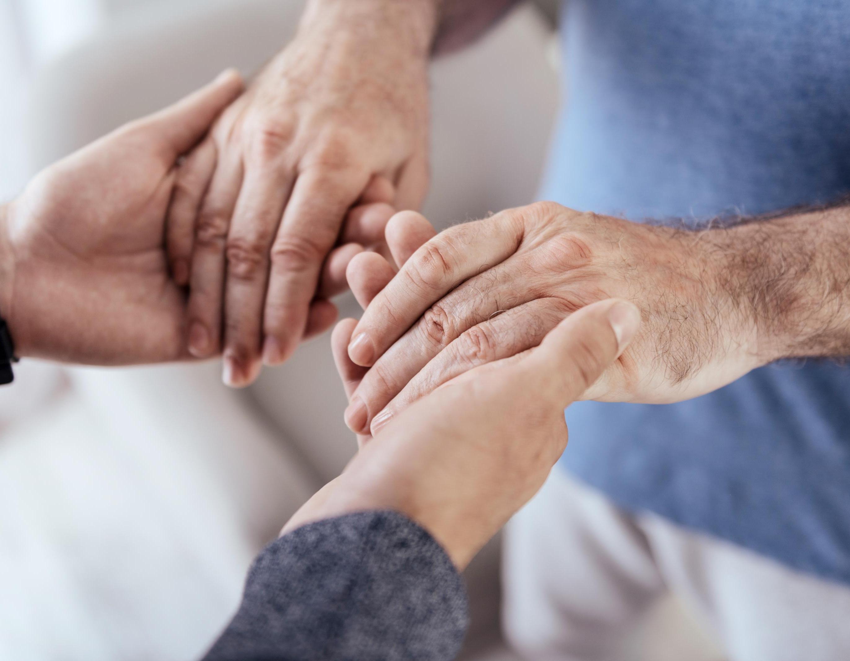 A person holding an older adult's hands