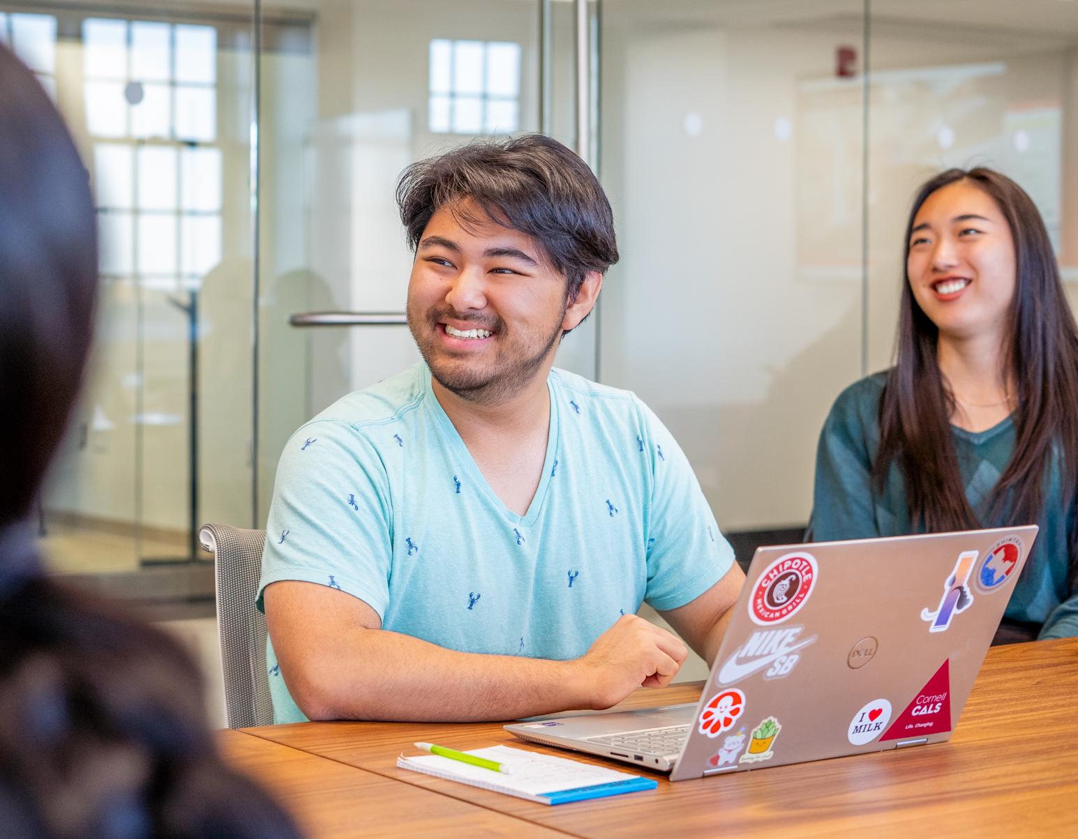 A student with a laptop smiles