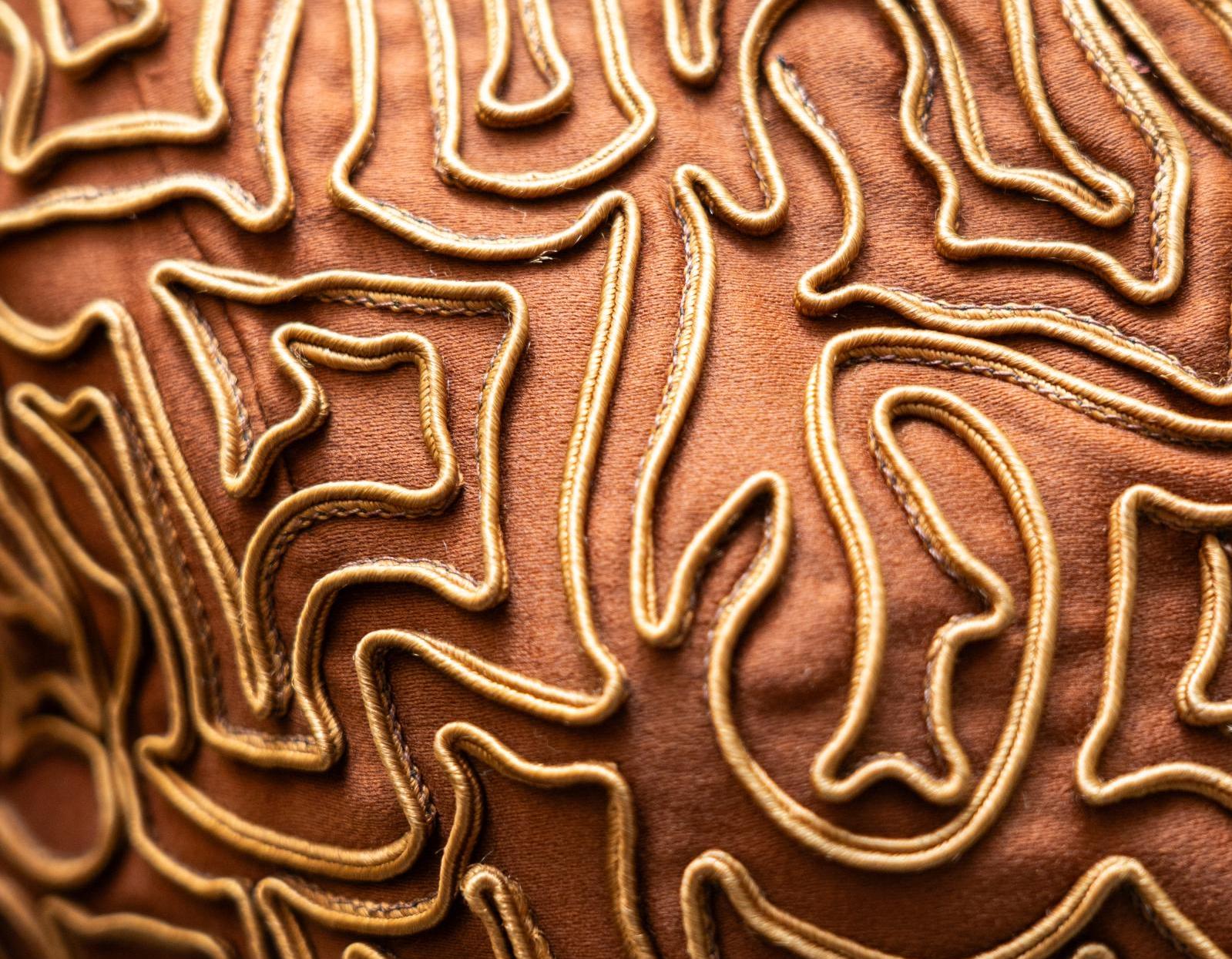 close up of brown fabric with yellow embroidery