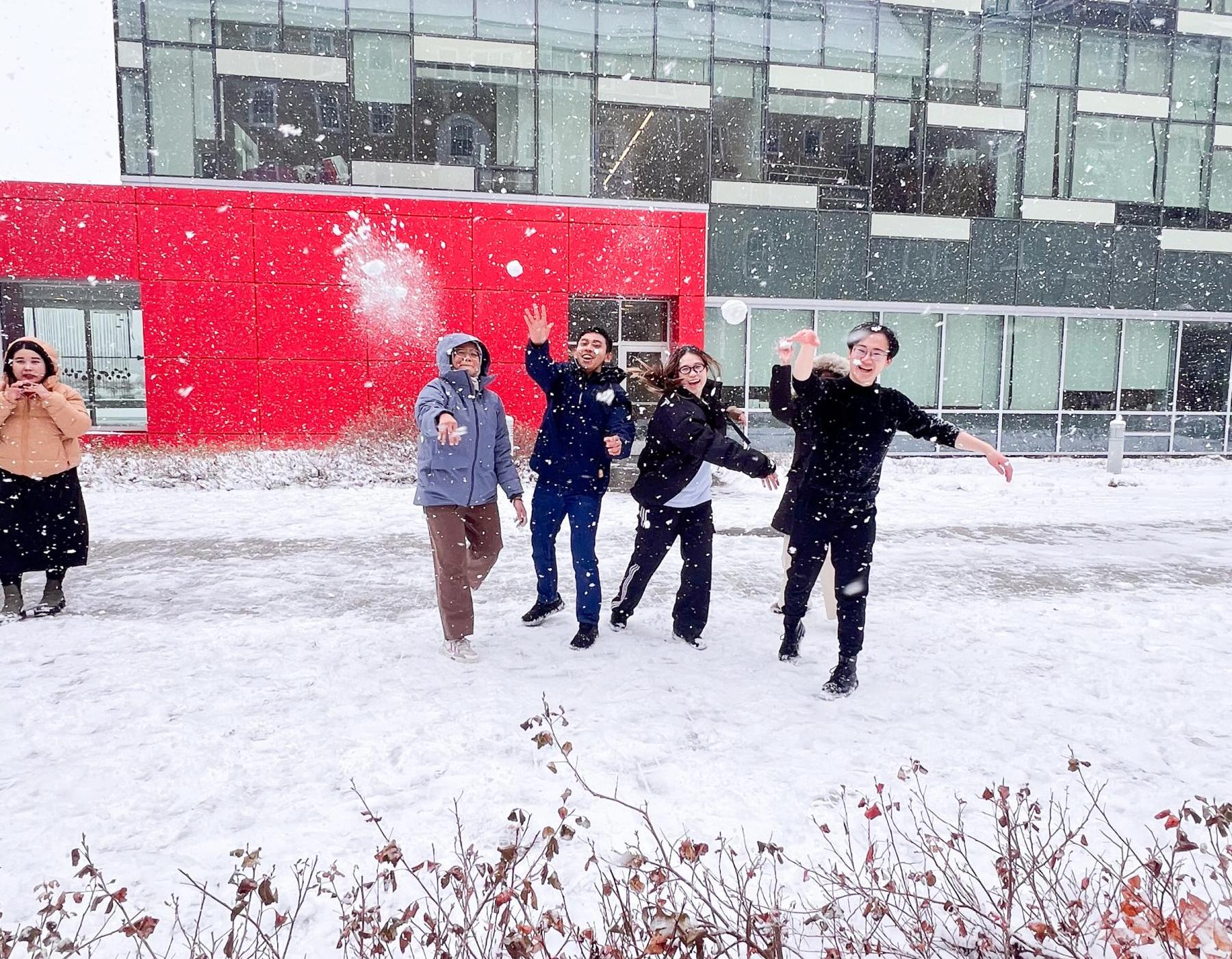 college students throwing snowballs in a courtyard