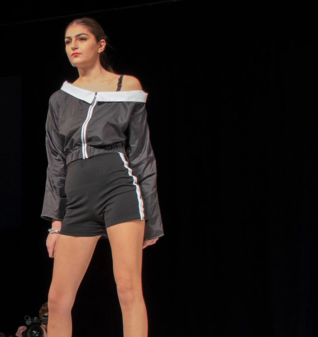 model in black and white shorts and off-shoulder top on the runway