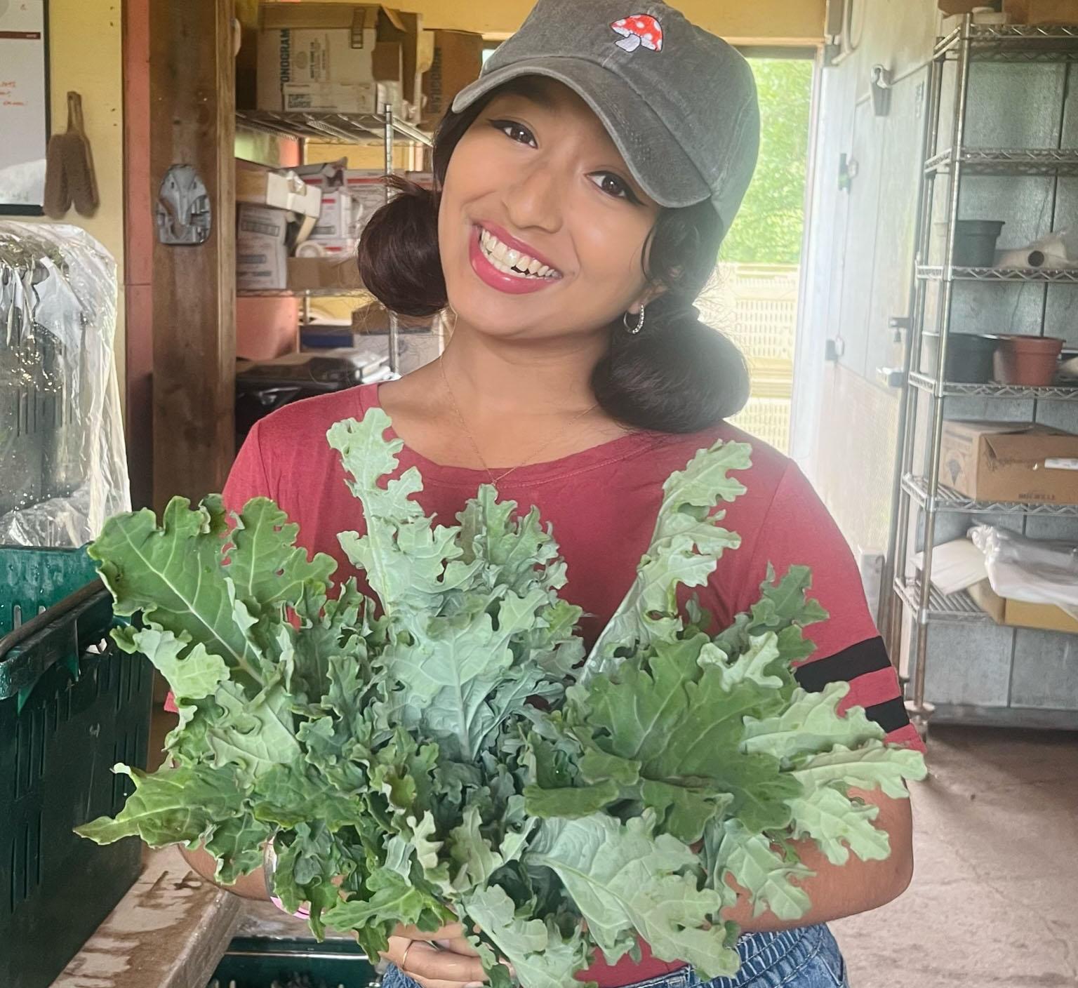Student Esha Shakthy proudly holds a bunch of freshly harvested kale