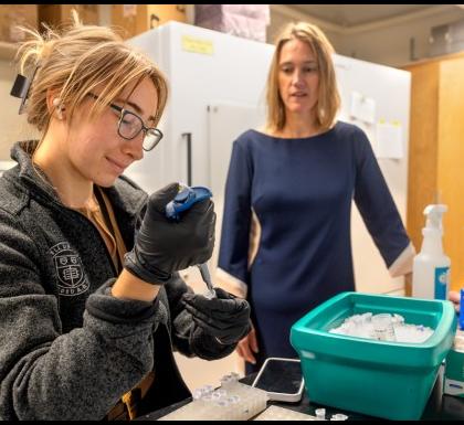 A graduate student fills a pipette int the Field Lab as Martha Field looks on.