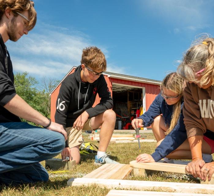 Cornell Cooperative Extension Jefferson County community school coordinator Donna Jean Coleman (right) helps LaFargeville Central School students Alexander Moore (far left), Samuel Duffany and Ella Hunneyman screw together boards on a flower box they built for a student-led community beautification project.
