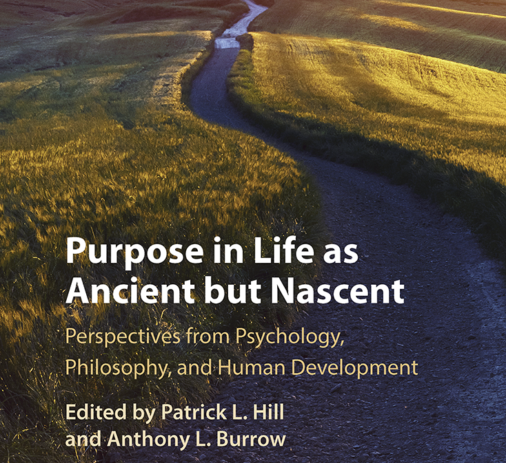 A cover of a book that is a winding road leading to a tree with mountains in the background