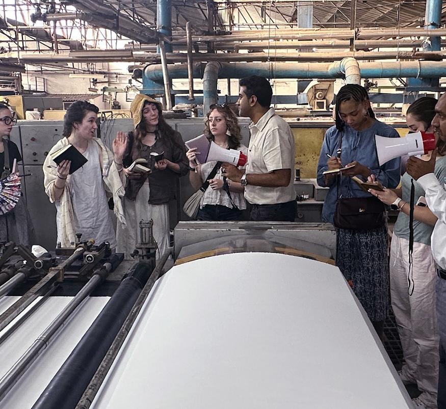 Students talk on a plant floor to textile workers