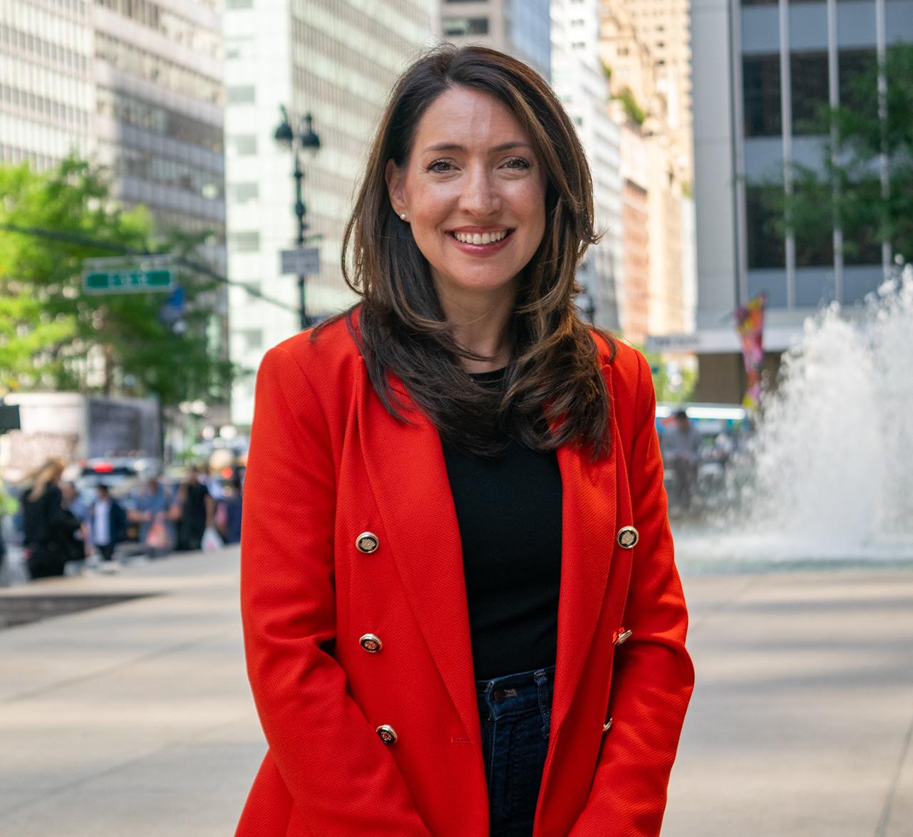 a woman stands in front of a fountain in the middle of New York City