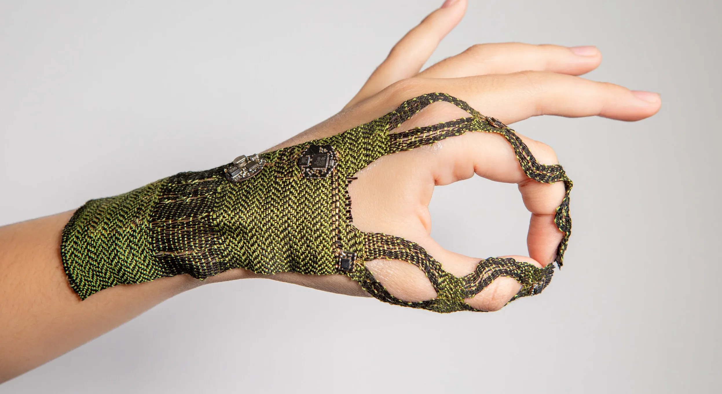 A hand with green woven textile on it.