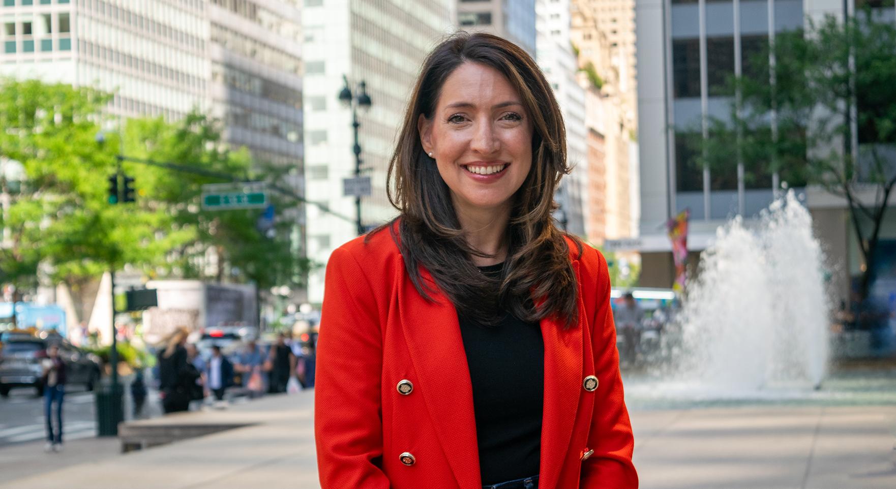 a woman stands in front of a fountain in the middle of New York City