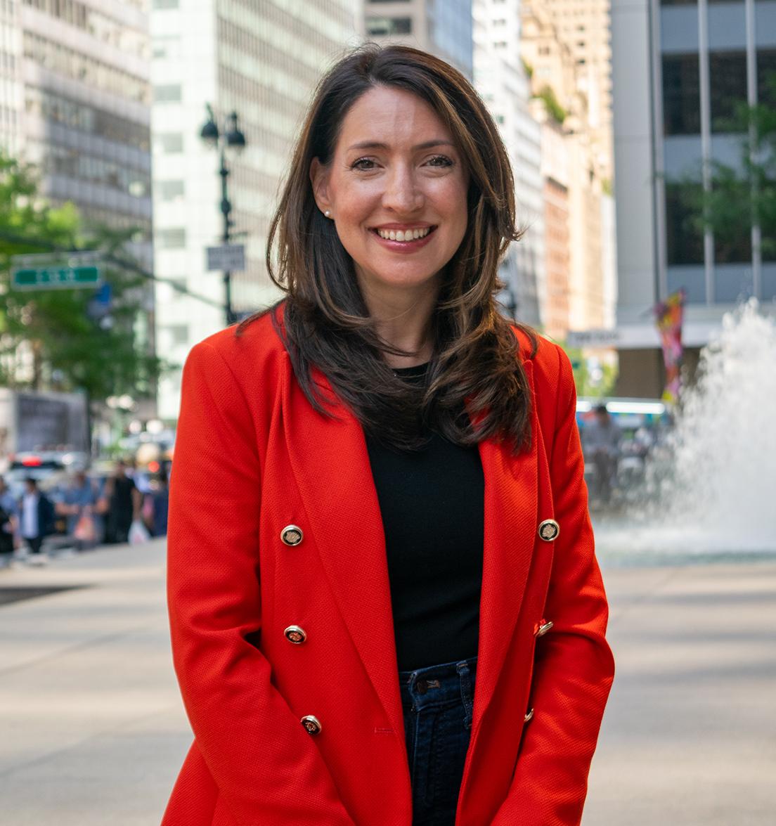 a woman stands in front of a fountain in the middle of New York City
