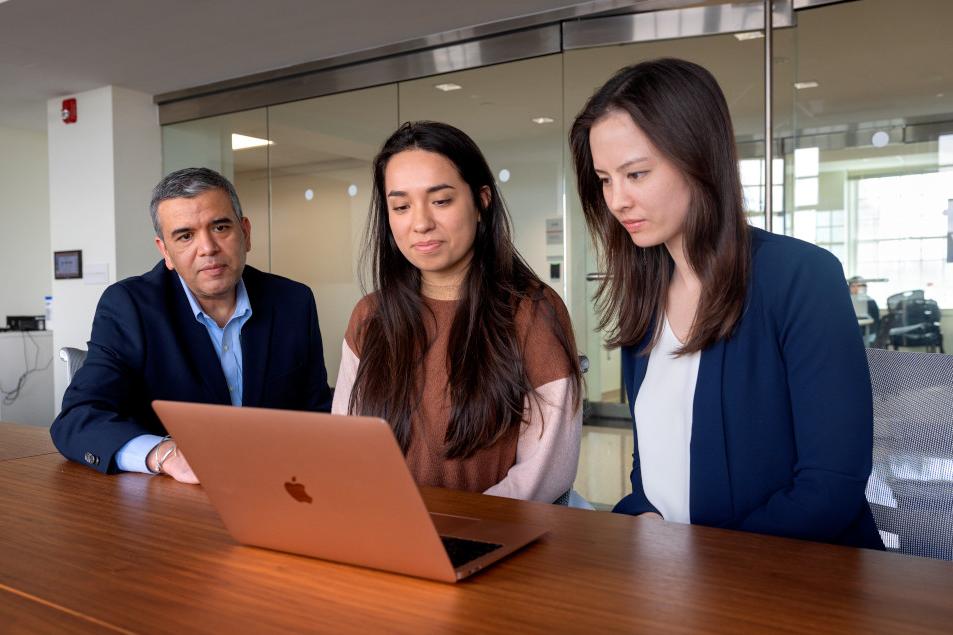 a man and two women looking at a laptop