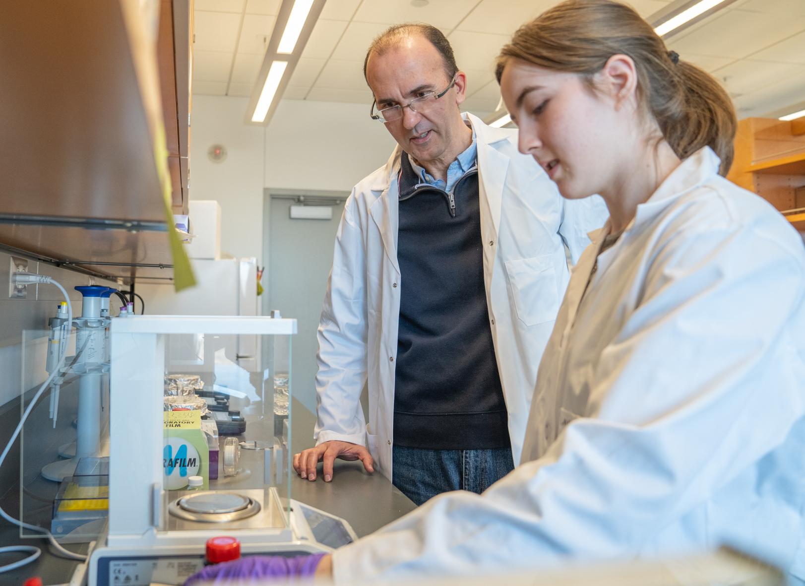 professor and undergraduate in a lab looking at equipment