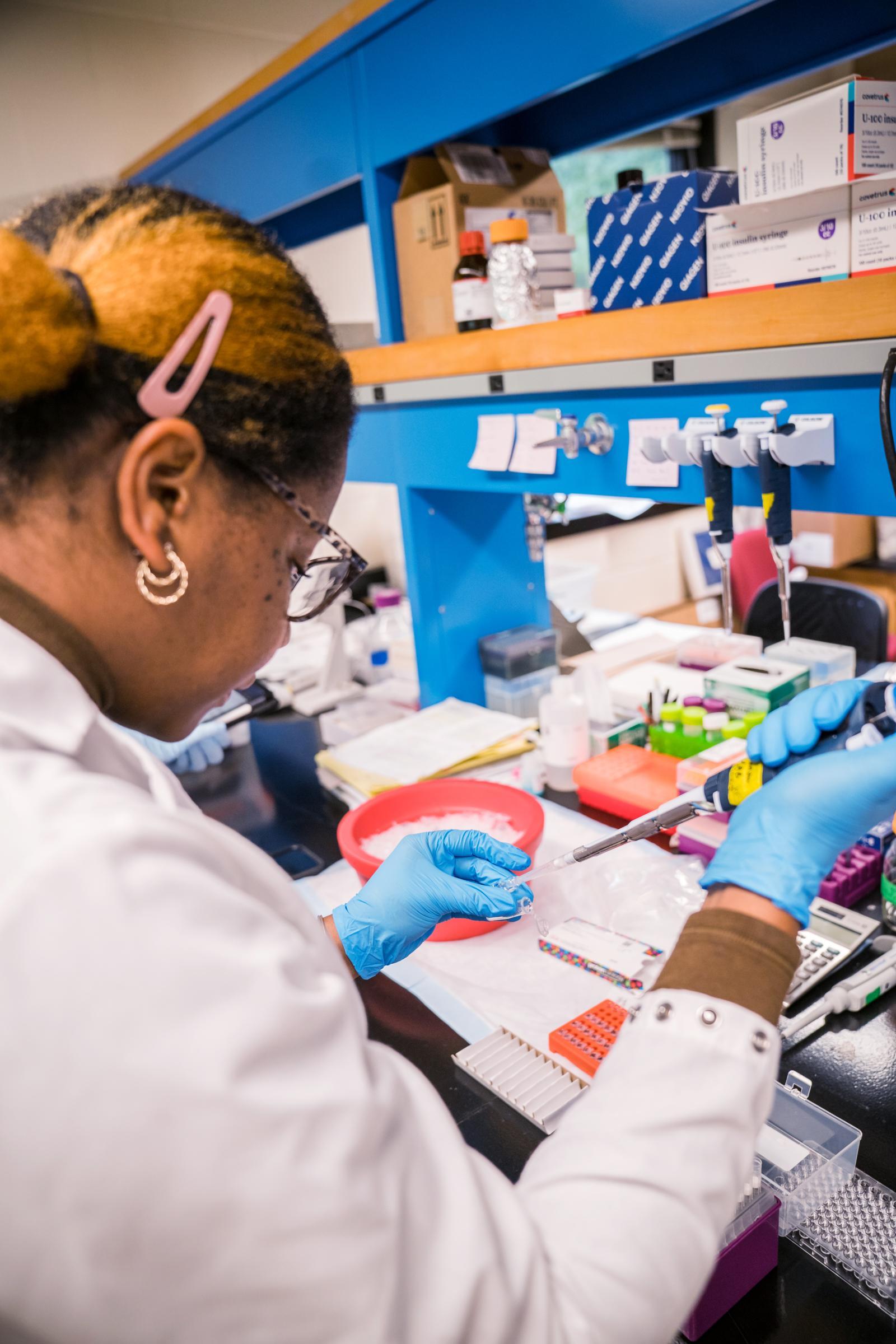 A researcher fills a pipette with liquid in the Barrow Lab.