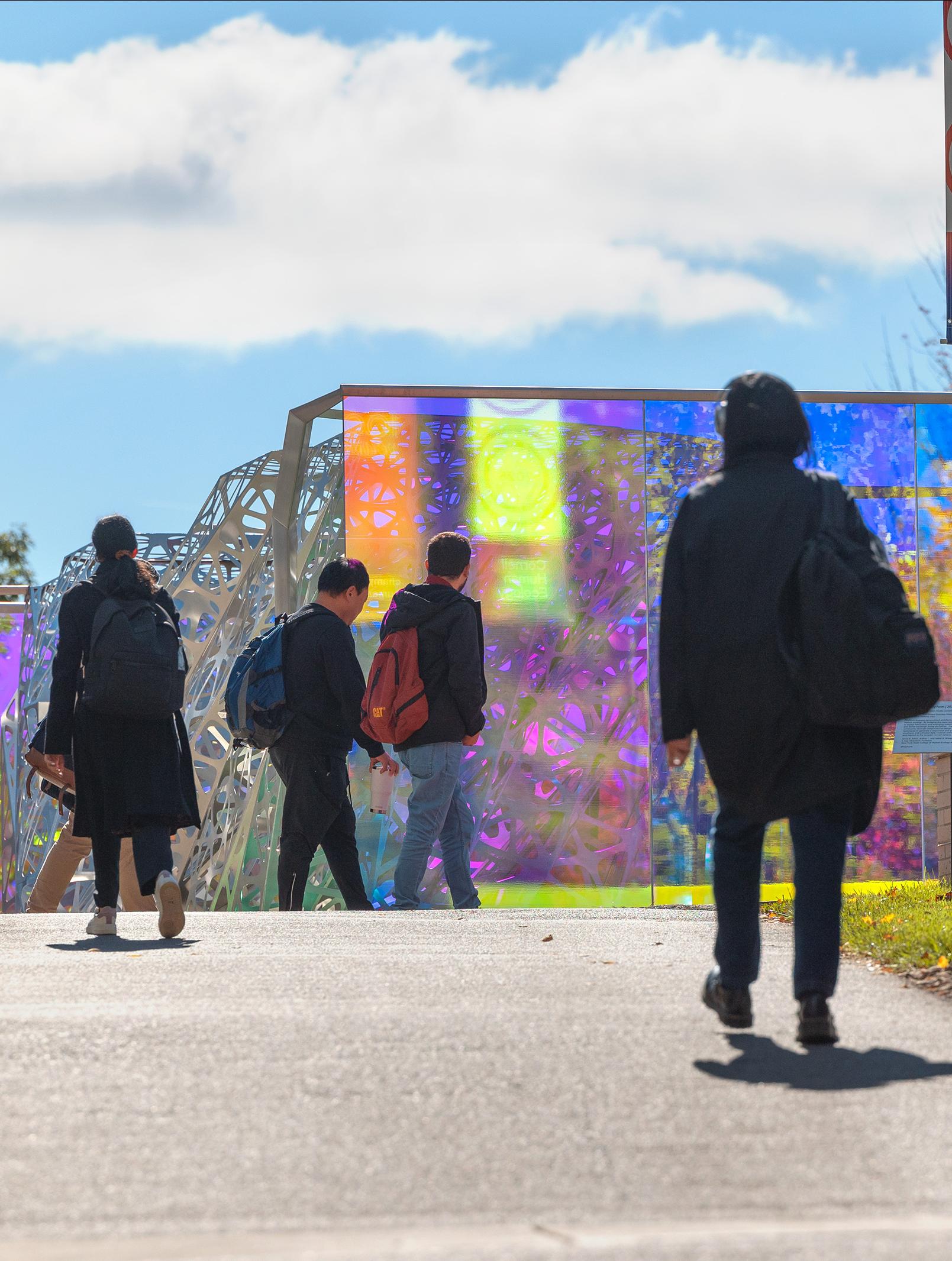 college campus with students walking towards an outdoor sculpture