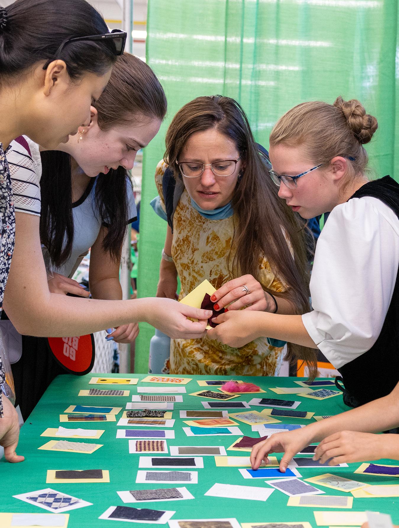 professor, students, and children look at cards on a table 