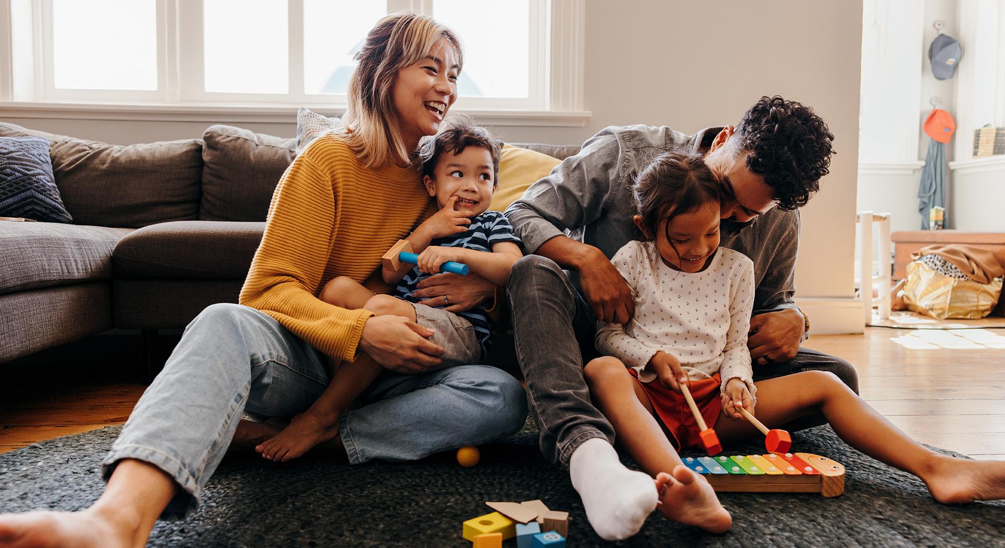two parents sitting on the floor playing with their children