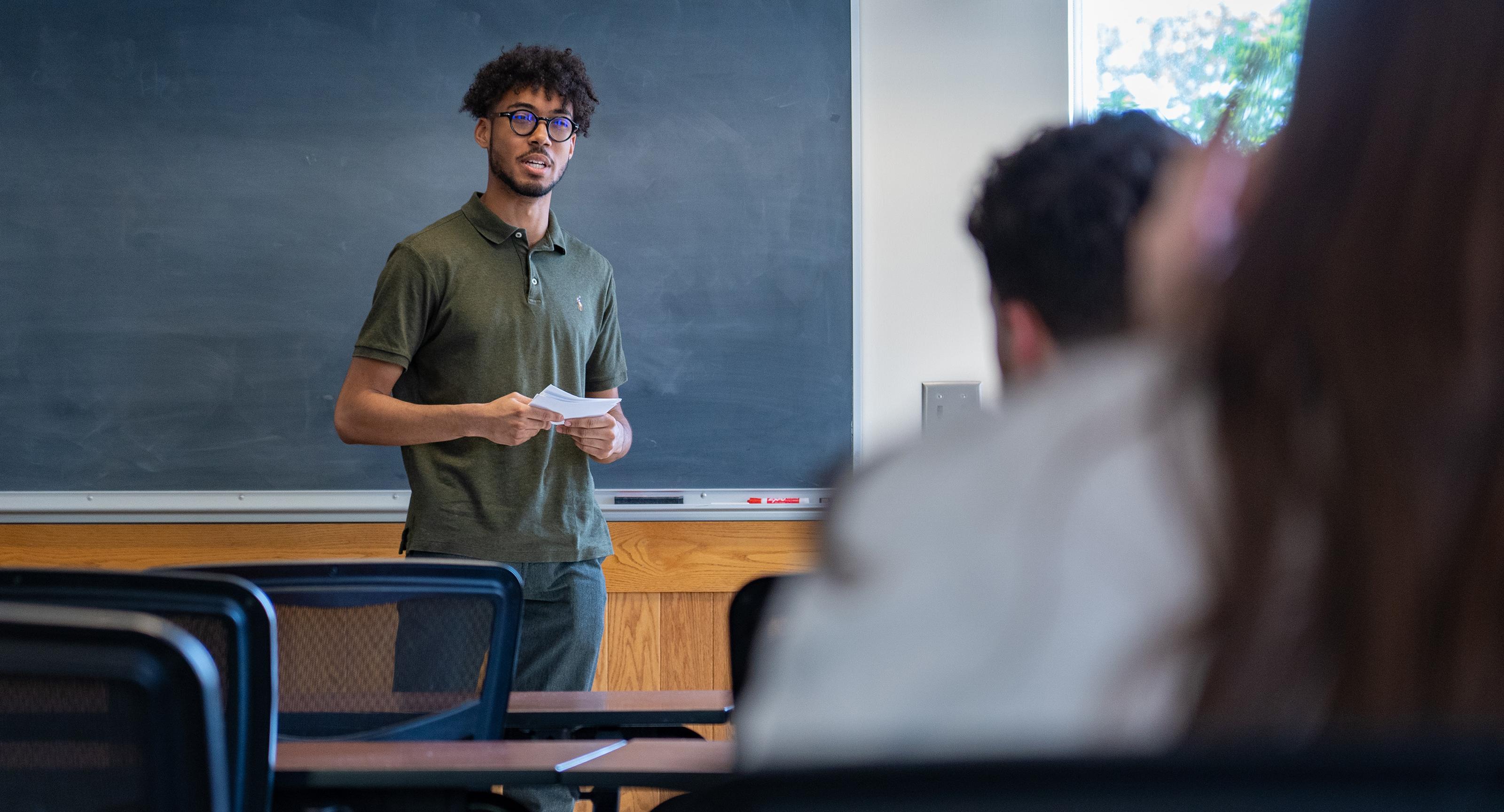 young man speaking in front of a classroom