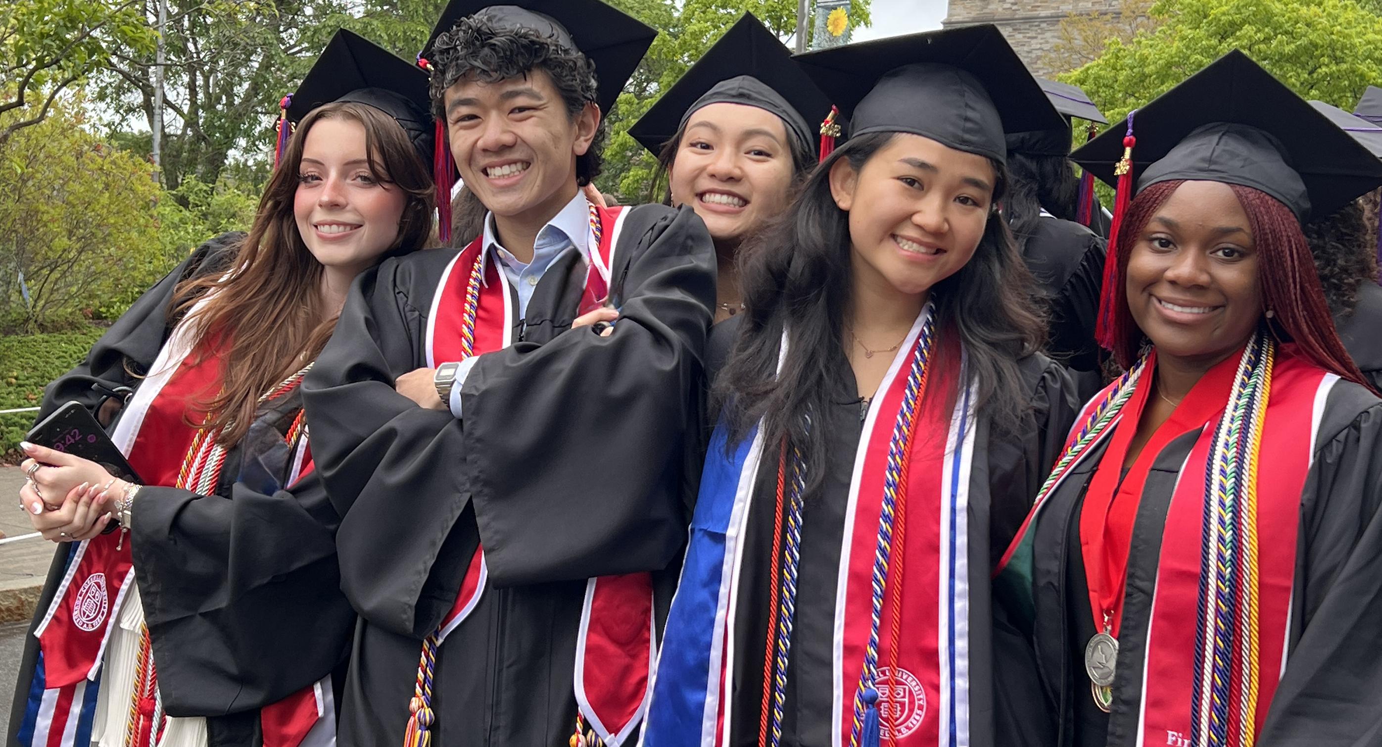 5 college students in cap and gown smiling