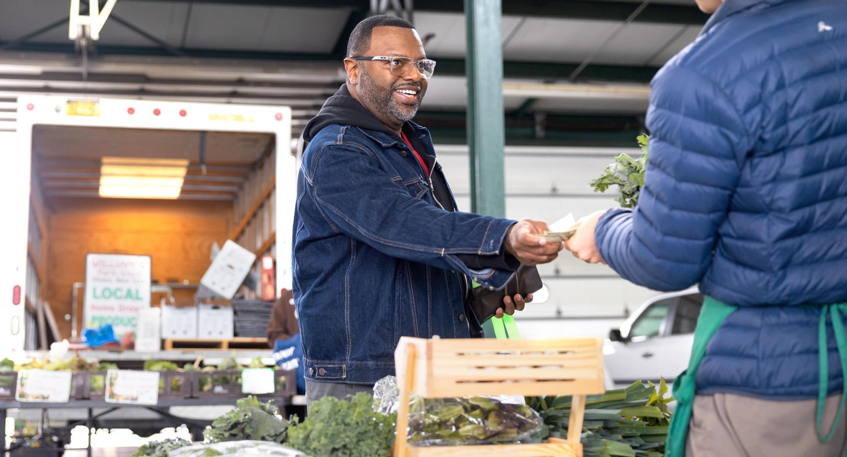 man paying for vegetables at a farmers market