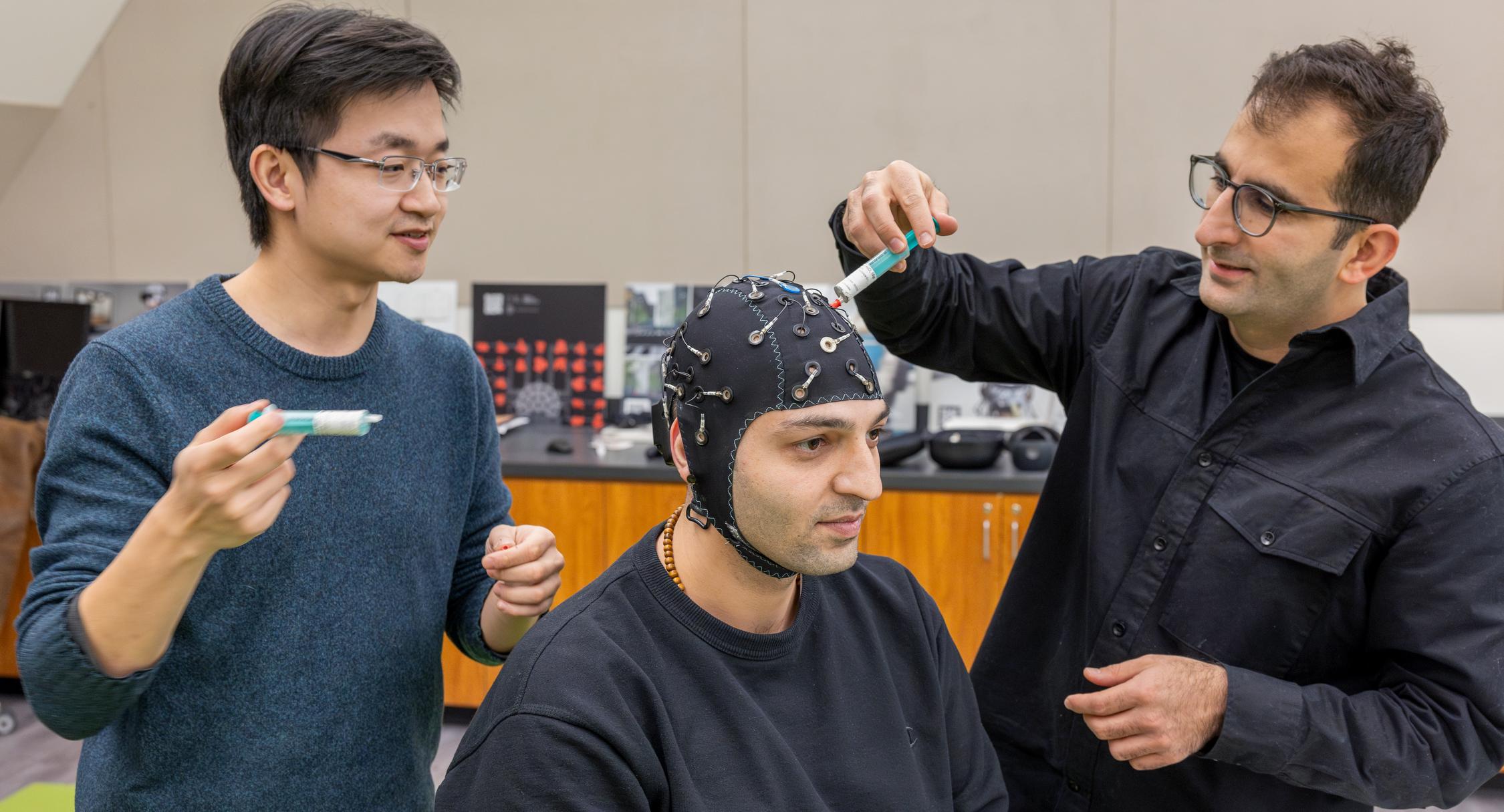 professor and grad student add gel to an EEG cap on a subject