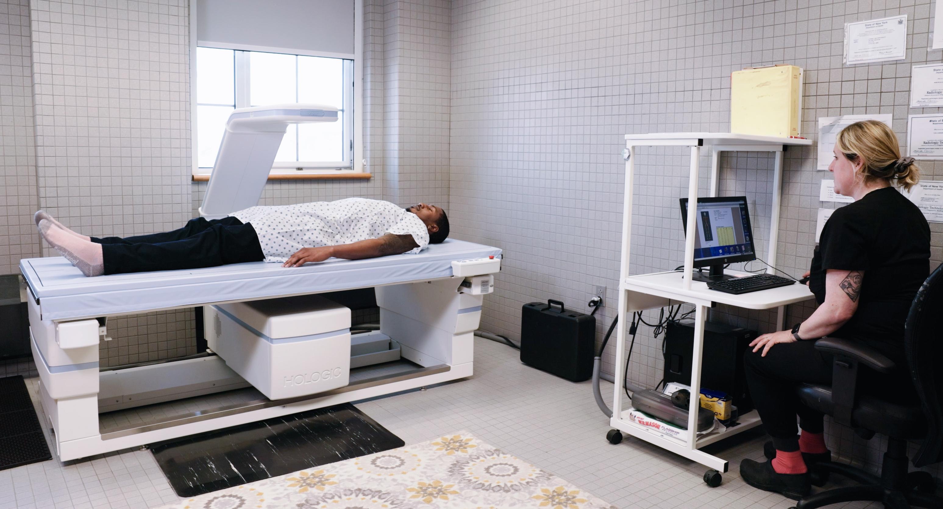 subject lying in an open scanner as a tech sits nearby at a laptop