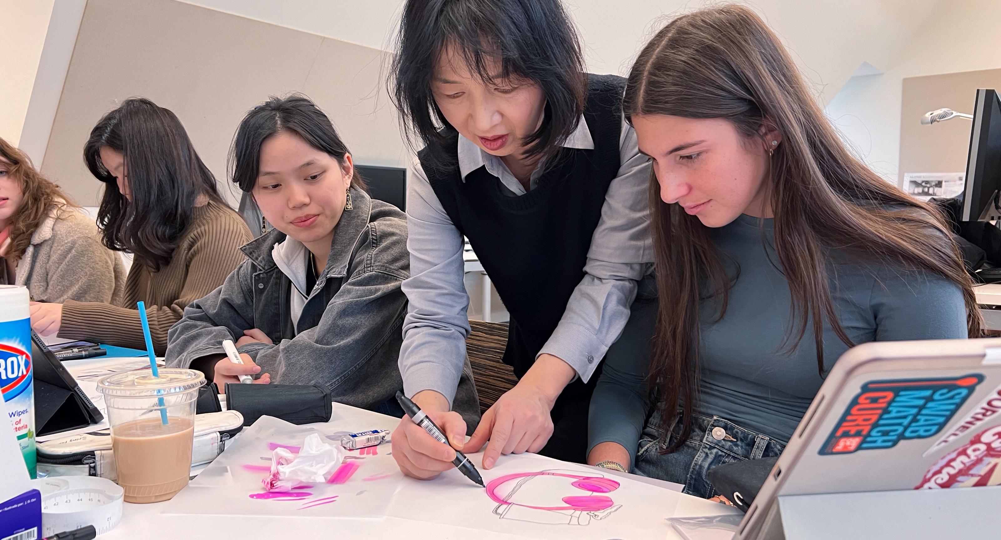 professor making notes on a student's drawing in a design class