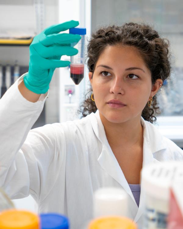 Angelina Mejia holds up a human sample in a test tube.