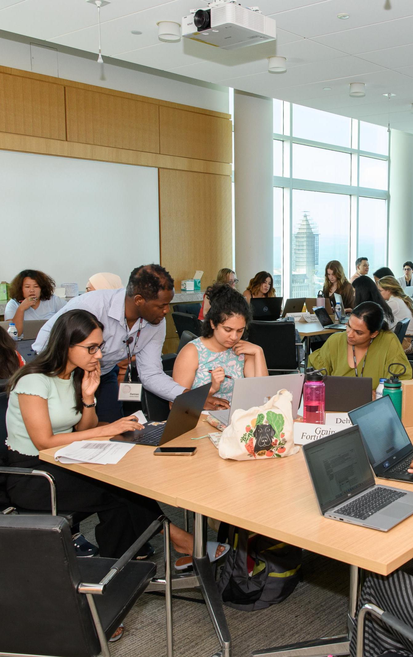 An instructor assists participants working at tables during the 2024 Summer Institute
