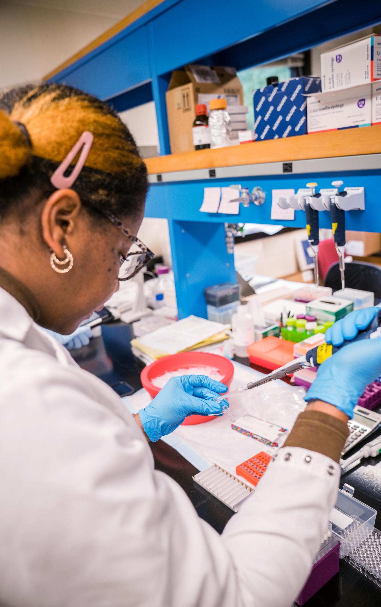 A researcher fills a pipette with liquid in the Barrow Lab.
