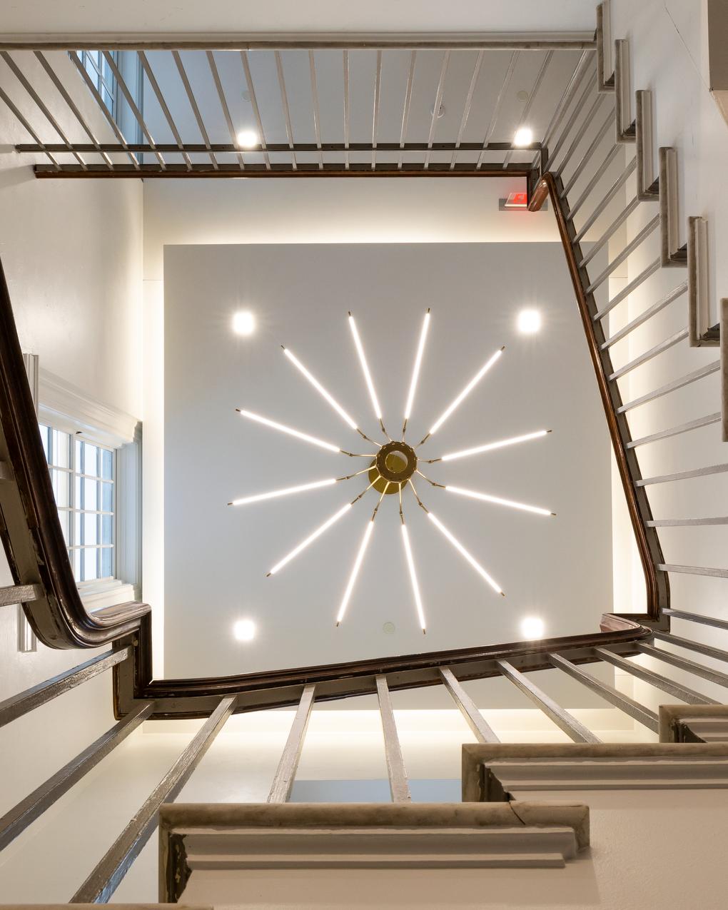 looking up a stairwell at a spoked light fixture